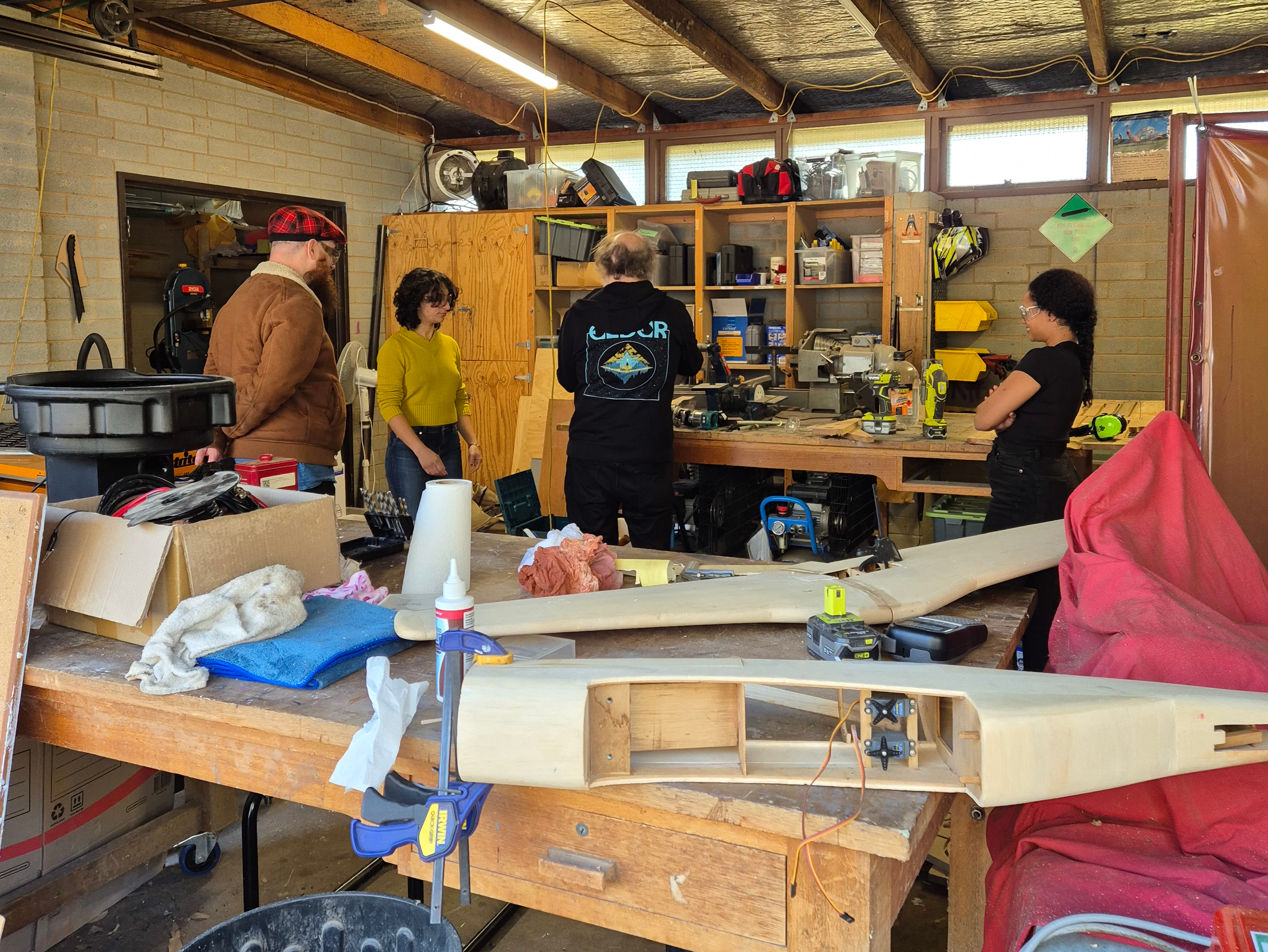 Four people discussion a problem around a workbench