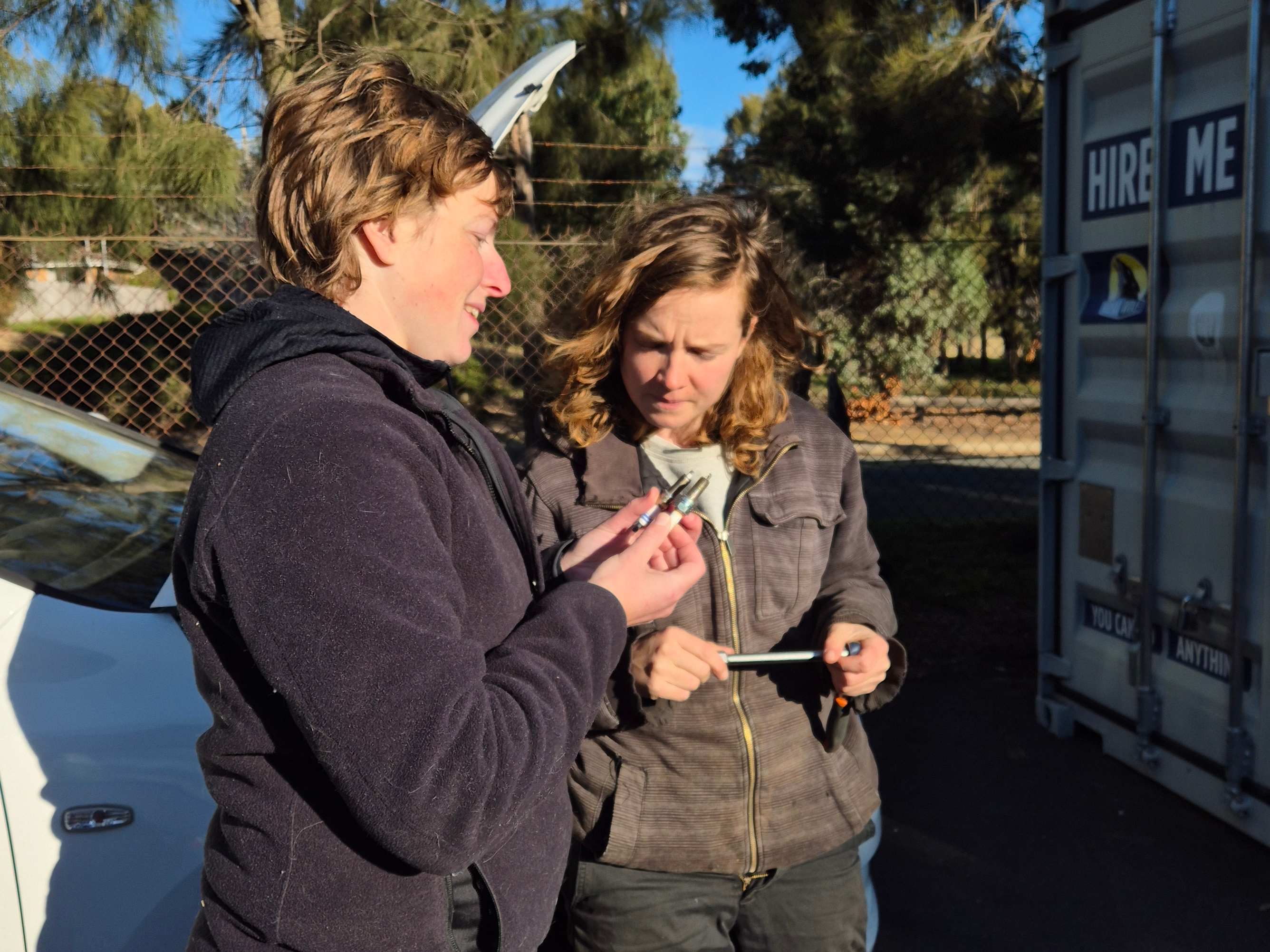 Two women examining spark plugs